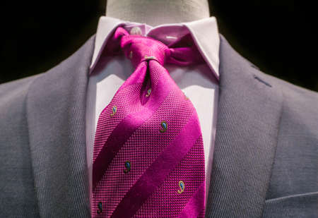 Close-up of a grey jacket with white striped shirt and bright magenta tie on black background の写真素材