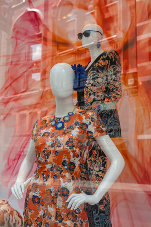 Two colourful mannequins with bright colourful dresses in a shop window  A street scene reflecting...