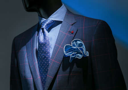 Close-up of a blue   red checkered jacket with checkered blue shirt, patterned blue tie and handkerchief on dark background の写真素材