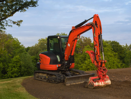Medium-sized red and black excavator at a construction site  Trees on the background 