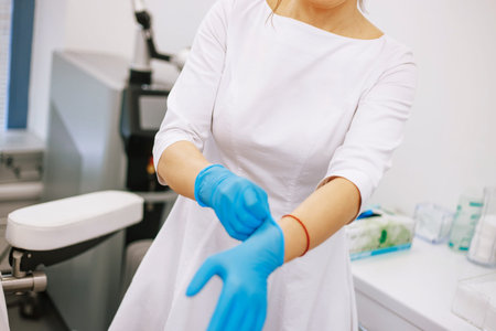 Doctor, nurse, woman puts on gloves before the procedure.の写真素材