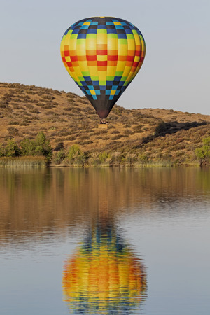 Hot air balloon flying above California lakeの写真素材
