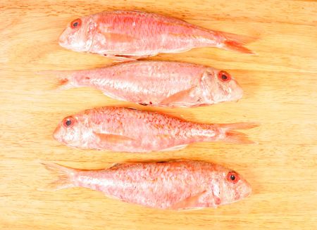 Four red mullet fish on a boardの写真素材