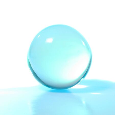 Turquoise crystal ball with reflection against whiteの写真素材