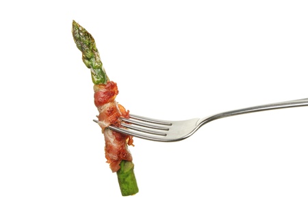 Cooked asparagus spear wrapped in pancetta ham on a fork isolated against whiteの写真素材