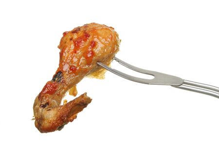 Barbecued chicken leg with tomato relish on a barbecue fork isolated against whiteの写真素材