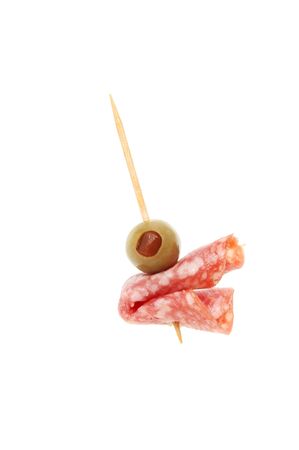 Olive and salami on a cocktail stick isolated against whiteの写真素材