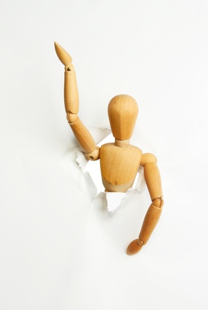 Artists wooden manikin emerging through a tear in white paperの写真素材