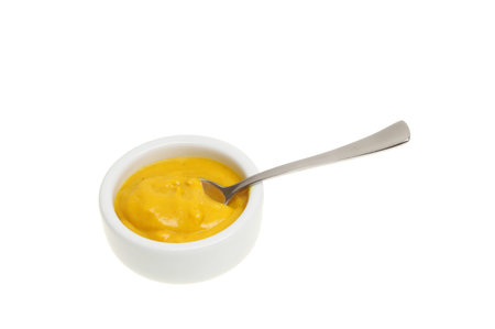 English mustard in a ramekin with a spoon isolated against whiteの写真素材