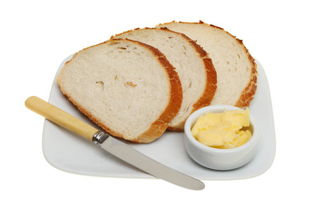 Slices of giraffe bread on a plate with a knife and a ramekin of butter isolated against white