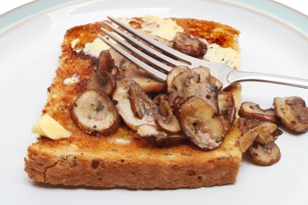 Closeup of chestnut mushrooms on toast with a forkの写真素材