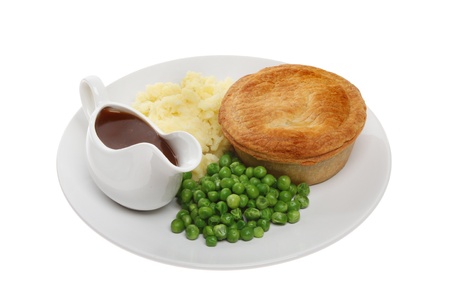 Savory pie with mashed potatoes, peas and gravy in a jug on a plate isolated against whiteの写真素材
