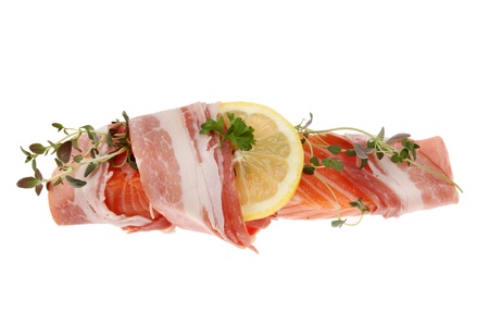 Salmon steak wrapped in pancetta with lemon and thyme isolated against whiteの写真素材