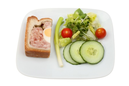 Slice of pork and egg gala pie with a slad garnish on a plate isolated against whiteの写真素材