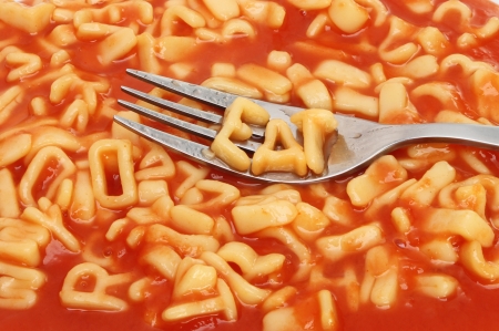 Fork with alphabet spaghetti spelling eat on a background of mixed alphabet spaghettiの写真素材