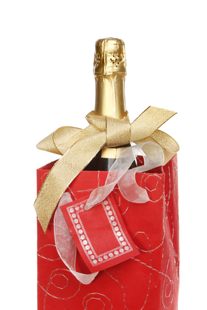 Champagne bottle in a decorative gift bag tied with a gold bow isolated against whiteの写真素材