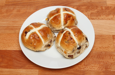 Hot cross buns on a plate on a wooden tableの写真素材