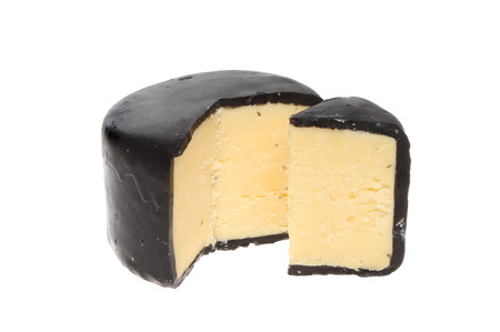 Truckle of mature Cheddar cheese with a slice cut out isolated against whiteの写真素材
