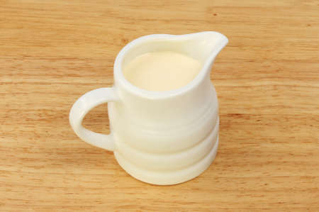 Jug of cream on a wooden boardの写真素材