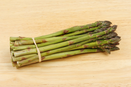 Bunch of fresh asparagus on a wooden boardの写真素材