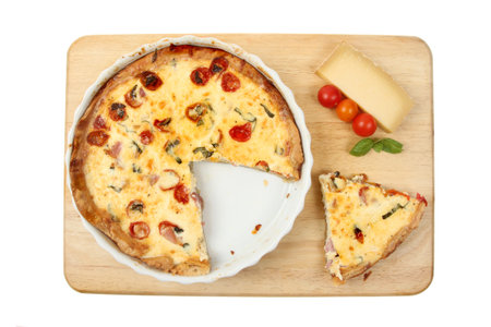 Roasted tomato and Gruyere cheese savory tart with ingredients on a wooden board isolated against...