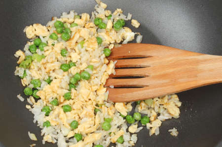 Closeup of egg fried rice in a non stick pan with a wooden spatulaの写真素材