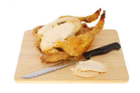 Roast chicken with a carving knife on a board isolated against whiteの写真素材