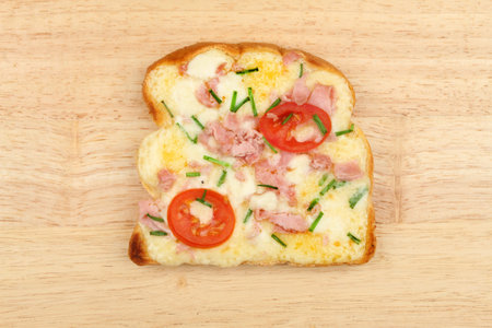 Mozzarella and Cheddar toasted cheese savory with ham, tomato and chives on a wooden board