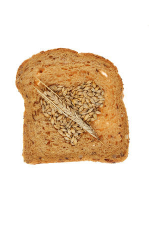 Slice of multi seeded bread with barley grains in a  heart shape with an ear of barley isolated against whiteの写真素材