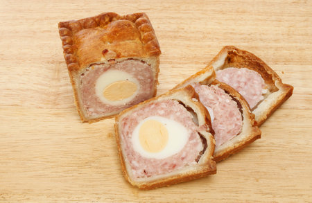 Pork and egg pie with cut slices on a wooden board