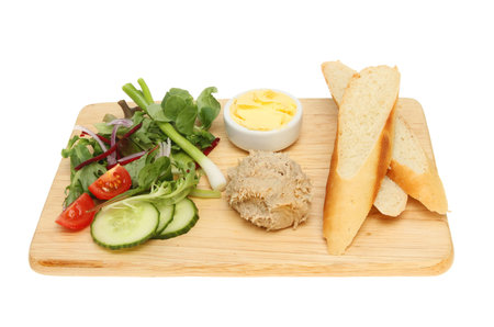 Mackerel pate, bread, butter and salad on a wooden board isolated against whiteの写真素材