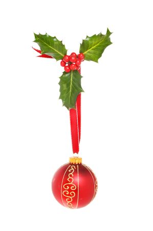 Christmas decoration, a sprig of holly with ribbon and a red and gold glitter bauble isolated against whiteの写真素材