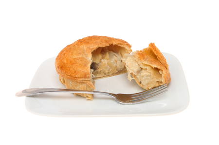 Puff pastry chicken and mushroom pie with a fork on a plate isolated against whiteの写真素材