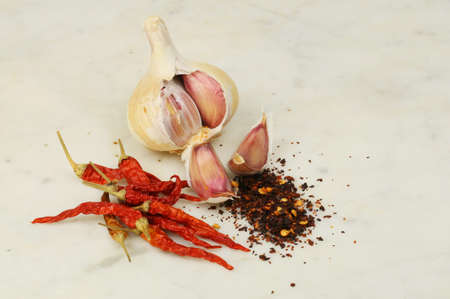 Garlic bulb and cloves with dried chilli peppers and flakes on marbleの写真素材