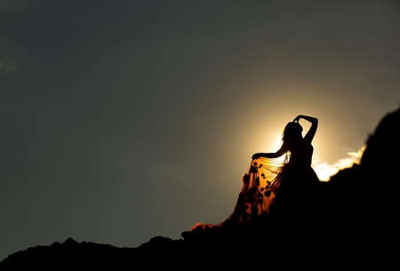 Woman silhouette in mountains, sunsetの写真素材