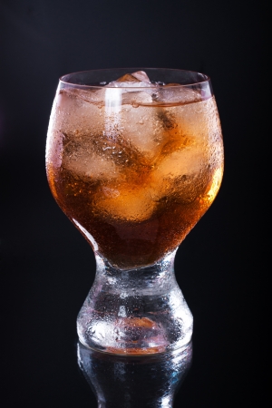 Whiskey with ice in a glass on a black backgroundの写真素材