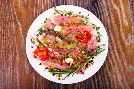 Raw fresh meat on a plate with condiments and fresh vegetablesの写真素材