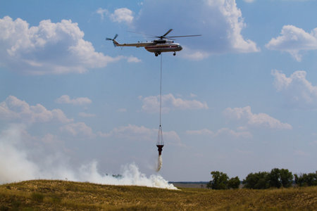 Firefighting helicopter attacks a wildfire with a cascading water release from its water bucket.の写真素材