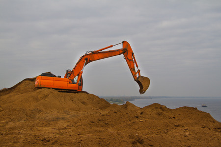 Orange excavator at work on a construction siteの写真素材