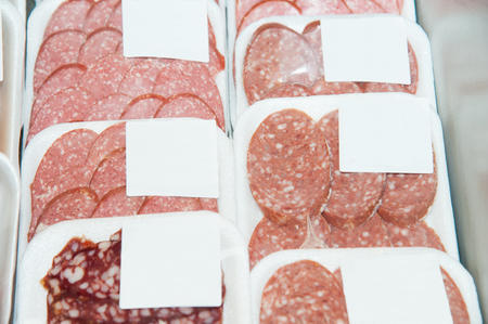 Variety of sausage slices in boxes in the window of a supermarketの写真素材