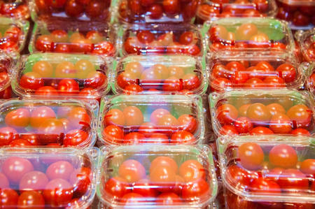 In plastic containers packed selective cherry tomatoes ready for sale in a vegetable shop. Cherry tomatoes packed in plastic containersの写真素材