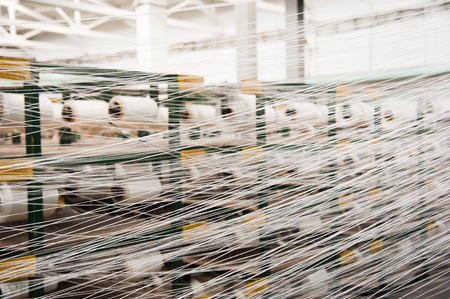 Textile industry - yarn spools on spinning machine in a textile factoryの写真素材