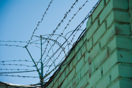Barbed wire fence stretched around prison wallsの写真素材
