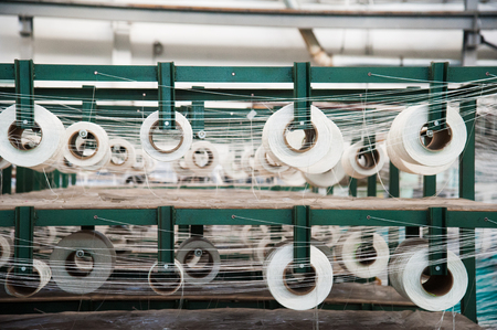 Textile industry - yarn spools on spinning machine in a textile factoryの写真素材