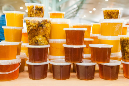 Honey in glass jars and bottles standing on the counter. Sale tasty and healthy product.