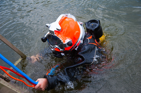 Diver in the water in a diving suit and helmet ready to diveの写真素材