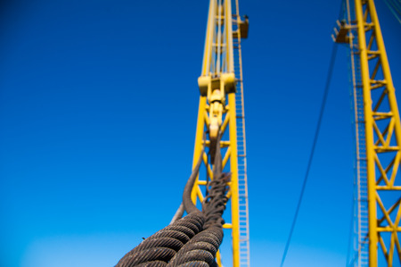 Loading in port. Floating port crane on blue sky background. Chains and hooks hoist with slings for loading in the port close-upの写真素材
