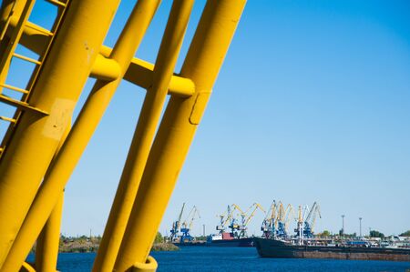 Loading in port. Floating port crane on blue sky background. Chains and hooks hoist with slings for loading in the port close-upの写真素材