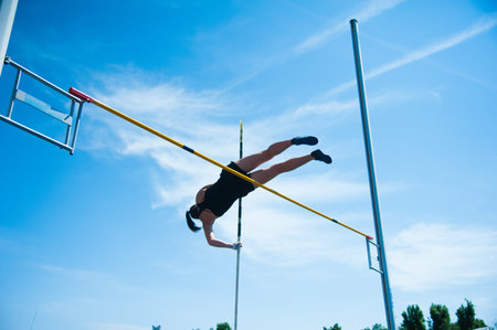 Competition pole vault jumper female on blue sky backgroundの写真素材