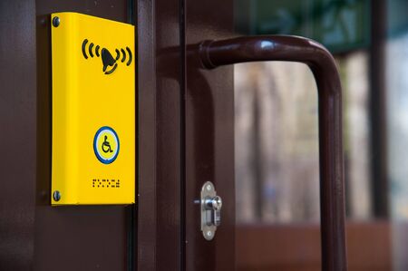 Disabled help call button. Yellow plate with the image of a disabled person and a call button. The complexity of restricting human movement.の写真素材